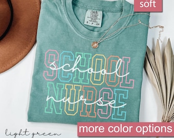 May include: A light green t-shirt with the text "school nurse" in rainbow colors. The shirt is made of a soft, comfortable material.