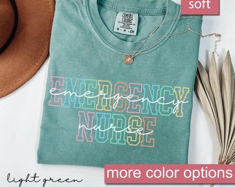 Może przedstawiać: Jasnozielony T-shirt z napisem "EMERGENCY NURSE" w kolorach tęczy. Koszulka wykonana jest z miękkiej, wygodnej tkaniny.