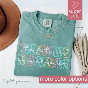 May include: A light green t-shirt with the text "the future is inclusive" in rainbow colors. The shirt is made of a soft, comfortable material.