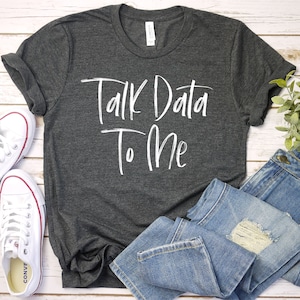 May include: A dark gray t-shirt with the text "Talk Data To Me" in white lettering.