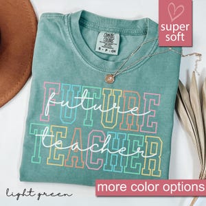 Może przedstawiać: Jasnozielony t-shirt z napisem "future teacher" w kolorze białym z tęczowymi obramowaniami. Koszulka wykonana jest z miękkiej, wygodnej tkaniny.