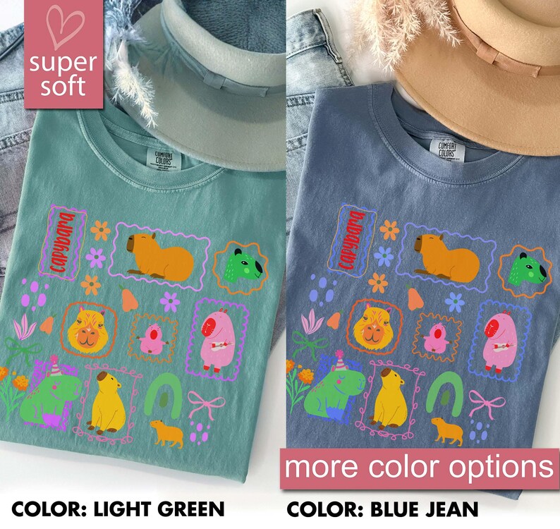 May include: Two t-shirts, one light green and one blue jean, featuring a colorful capybara graphic. The design includes various capybara illustrations within decorative frames, flowers, and the word "capybara". The shirts are labeled "super soft" and "more color options".