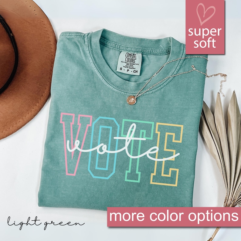 May include: Light green t-shirt with the word "VOTE" in colorful outlined letters. The shirt is made of a soft, comfortable fabric.