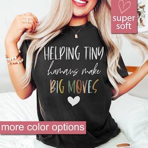 May include: A black t-shirt with the text "HELPING TINY humans make BIG MOVES" in colorful letters. The shirt is super soft and has a white heart in the bottom center.