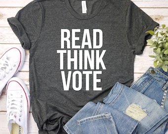 May include: A dark gray t-shirt with the words "READ THINK VOTE" printed in white.
