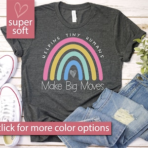 May include: A dark grey t-shirt with a rainbow graphic and the text "Helping Tiny Humans Make Big Moves".