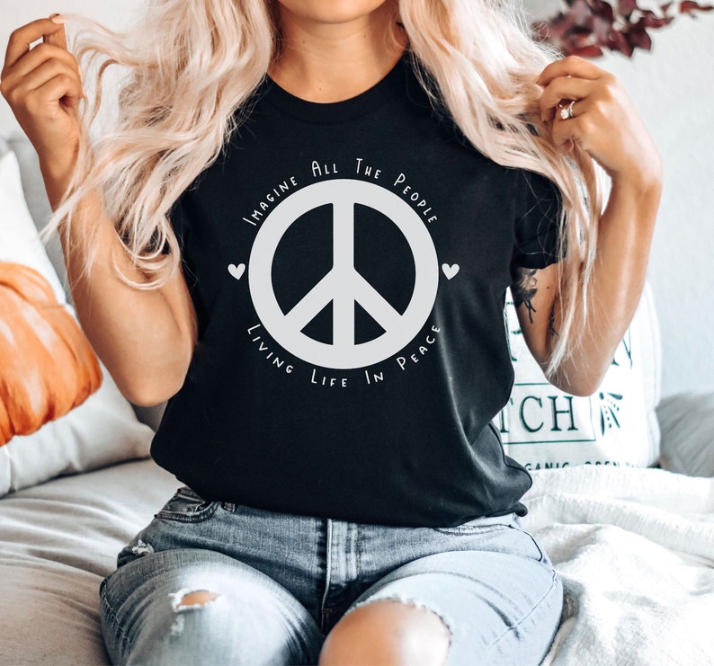 May include: Black t-shirt with a white peace sign and the text "Imagine All The People Living Life In Peace".