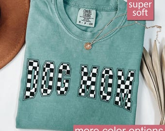 May include: A light green t-shirt with the words "DOG MOM" in black and white checkered print. The shirt is made of a soft, comfortable fabric.