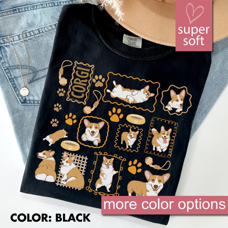 May include: Black t-shirt featuring multiple illustrations of Corgi dogs in various poses, along with paw prints and the word "CORGI". The shirt also has the words "super soft" and "more color options".