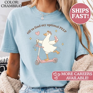 May include: Light blue chambray t-shirt featuring a cartoon duck riding a pink scooter, holding a stethoscope and a vial. Text reads "Off to find my optimal PEEP" and "MORE CAREERS AVAILABLE!".
