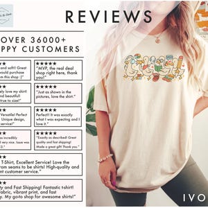 May include: Ivory-colored t-shirt featuring a line of cartoon ducks with school-themed accessories. The shirt has the word "Reviews" at the top and customer reviews on the left side. The shirt is a comfortable fit.
