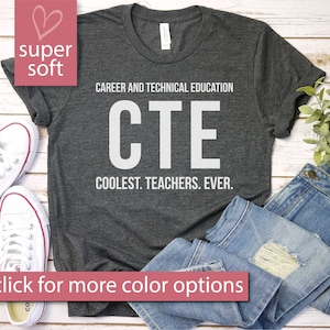 Könnte beinhalten: Dunkelgraues T-Shirt mit dem weißen Text „CAREER AND TECHNICAL EDUCATION CTE COOLEST. TEACHERS. EVER.“. Das Shirt wird mit blauen Jeans und weißen Turnschuhen kombiniert. Das Bild enthält auch den Text „super soft“ und „click for more color options“.