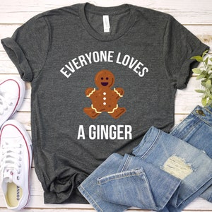 May include: A dark grey t-shirt with the text "Everyone loves a ginger" in white. A gingerbread man graphic is in the centre of the shirt.