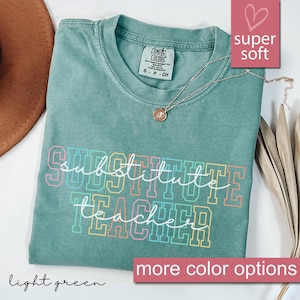May include: Light green t-shirt with the text "substitute teacher" in rainbow colors. The shirt is made of a soft, comfortable fabric.