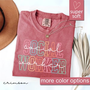 May include: Crimson red t-shirt with the text "social worker" in rainbow colors. The shirt is made of a soft, comfortable fabric.