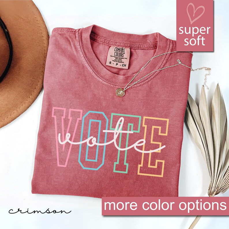 May include: Crimson red t-shirt with the word "VOTE" in rainbow colors. The shirt is made of a soft, comfortable fabric.  "Super soft" and "more color options" are written in the image.