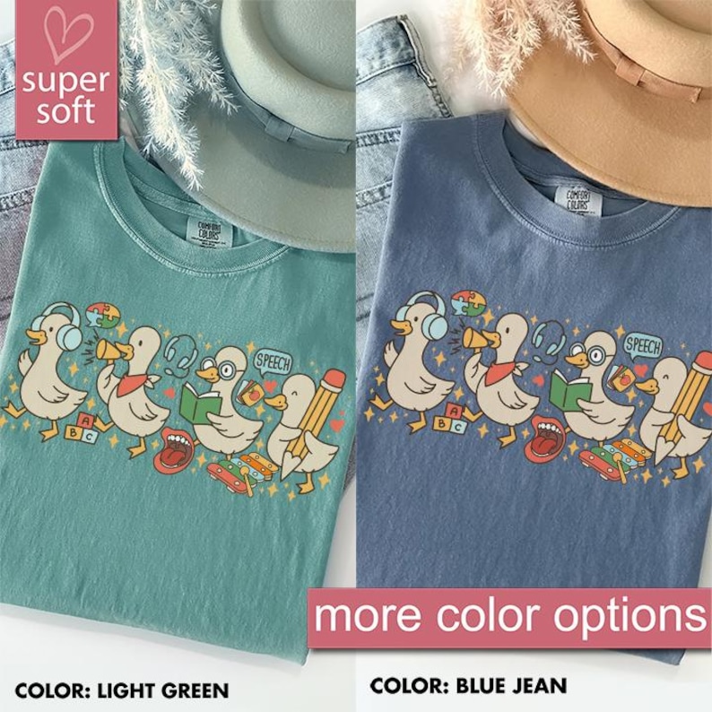 May include: Light green and blue jean t-shirts with a graphic of cartoon ducks wearing headphones and holding school supplies. The text "SPEECH" is in a speech bubble. The shirts are labeled "super soft" and "more color options".