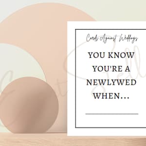 May include: A white card with black text that reads "Cards Against Weddings" and "You know you're a newlywed when..." with a blank line for filling in the answer.