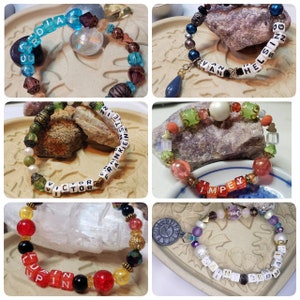 May include: A selection of beaded bracelets in diverse colour palettes, each with text. The bracelets spell out names such as "ARDIA", "VAN HELSIS", "VICTOR FRANKENSTEIN", "IMPEY", "LUPIN", and "BERMAN". The beads are of various shapes and sizes.