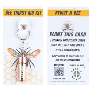 May include: A "Bee Thirst Aid Kit" with a keychain featuring a copper-coloured vial and a bee graphic. The card reads "Plant this card" and contains wildflower seeds to help save bees. Includes a QR code and the text "Made in Devon."
