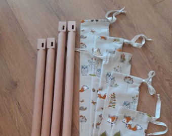 May include: Four wooden dowels with a square cut-out at each end. The dowels are arranged vertically and are next to five fabric pouches with a white background and a pattern of owls, foxes, and leaves in shades of brown, orange, and green.
