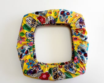 May include: Yellow fabric chair cover with a colorful print of sugar skulls and flowers.