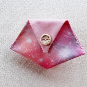 May include: A pink fabric coin purse with a galaxy print and a wooden button that says "Handmade with love".