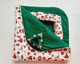 May include: A green and white Christmas-themed baby blanket with a pocket on the front. The blanket is made of soft fabric and is perfect for keeping a baby warm and cozy.