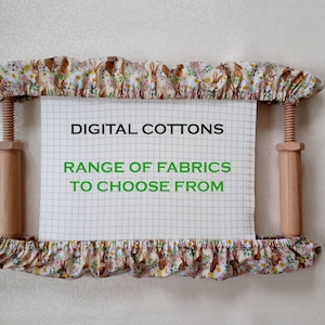 May include: A wooden embroidery hoop with white fabric stretched across it. The fabric has a grid pattern and the text "DIGITAL COTTONS RANGE OF FABRICS TO CHOOSE FROM" is printed in green.