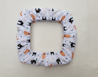 May include: White fitted chair cover with a black cat and orange hot dog pattern. The cover has an elastic band around the edge.