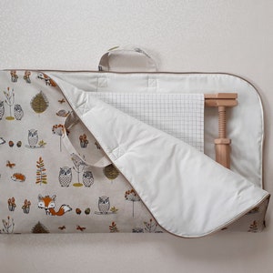 May include: A beige fabric carrying case with a woodland animal print featuring owls, foxes, and mushrooms. The case has a white interior and a wooden screw clamp is visible. A handle is attached for carrying.