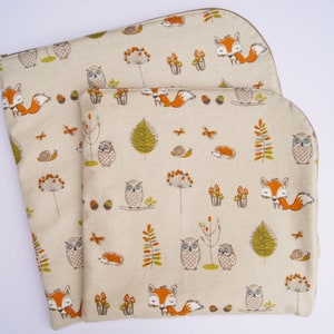 May include: Two beige fabric zippered pouches with a woodland animal print. The print features owls, foxes, and mushrooms in shades of orange, brown, and green.
