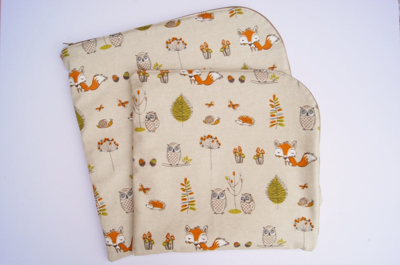 May include: Two beige fabric zippered pouches with a woodland animal print. The print features owls, foxes, and mushrooms in shades of orange, brown, and green.