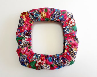 May include: Pink fabric chair cover with a colorful Day of the Dead skull and flower pattern.