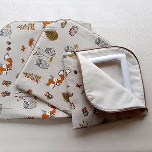 May include: Three fabric storage bags with a woodland animal print. The bags are lined with a white fabric and have a zipper closure. The print features owls, foxes, and mushrooms in shades of brown, orange, and green on a beige background.
