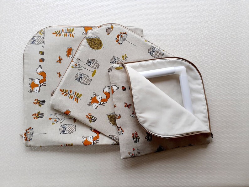May include: Three fabric storage bags with a woodland animal print. The bags are lined with a white fabric and have a zipper closure. The print features owls, foxes, and mushrooms in shades of brown, orange, and green on a beige background.