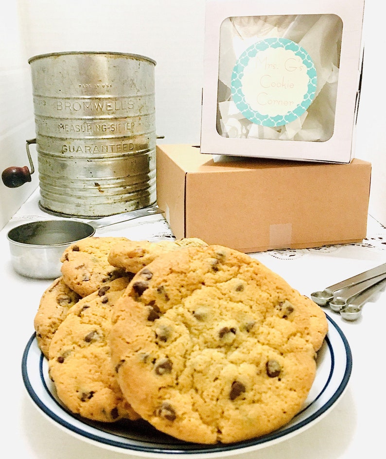May include: A plate of freshly baked chocolate chip cookies. The cookies are golden brown and have a crispy exterior with a soft and chewy interior. The cookies are arranged on a blue and white striped plate.