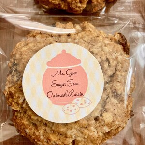 May include: A close-up of a sugar-free oatmeal raisin cookie in a clear plastic bag. The cookie has a label that reads "Ms. Goetz Sugar Free Oatmeal Raisin".