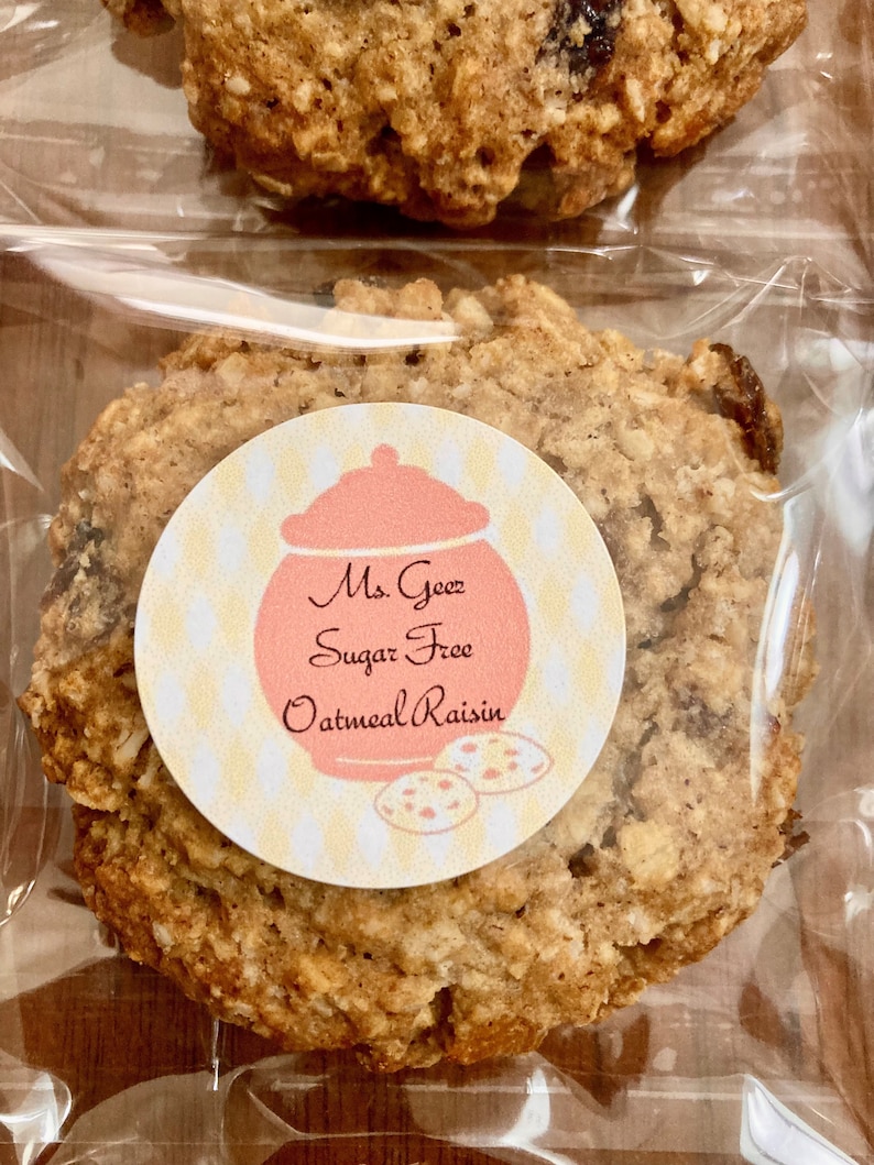 May include: A close-up of a sugar-free oatmeal raisin cookie in a clear plastic bag. The cookie has a label that reads "Ms. Goetz Sugar Free Oatmeal Raisin".