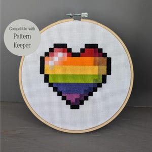 Op de afbeelding: Een regenboog pixel hart kruissteekpatroon in een houten borduurring. Compatibel met Pattern Keeper.