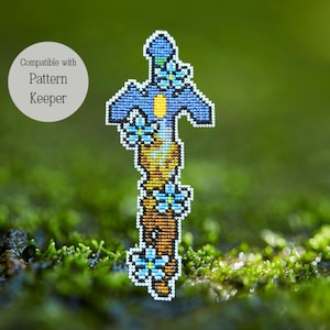 May include: A cross-stitch design of a blue and yellow sword adorned with blue flowers. The text "Compatible with Pattern Keeper" is in a white circle in the upper left corner. The sword is set against a blurred green background.