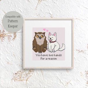 May include: Framed cross-stitch art featuring an owl and a dog with the text "You have two hands for a reason." The owl is brown and the dog is white. Two pink hearts are above the dog.