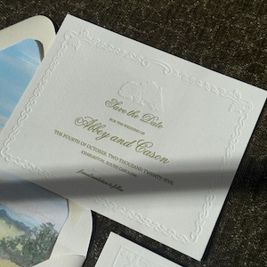Puede incluir: Invitación de boda blanca con borde floral en relieve y texto. El texto dice "Save the Date" para Abbey y Cason, con la fecha de la boda el 4 de octubre de 2025, en Charleston, Carolina del Sur. Se ve un paisaje en acuarela.