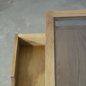 Puede incluir: Una mesa de centro de madera con tapa de cristal y un caj&oacute;n. La mesa est&aacute; hecha de madera marr&oacute;n claro y tiene un acabado natural.
