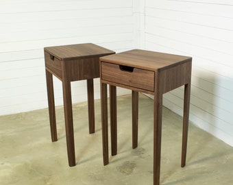 Puede incluir: Dos mesitas de noche de madera con un cajón cada una. Las mesitas de noche son de madera de nogal oscuro y tienen un diseño simple y moderno.