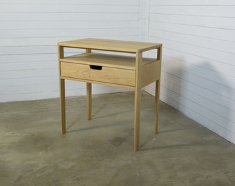 May include: A light wood end table with a single drawer and a shelf. The table has four legs and is made of solid wood.