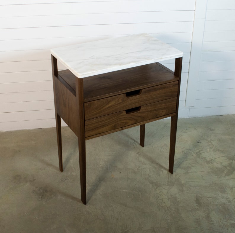 May include: A walnut wood end table with two drawers and a white marble top.