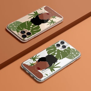 May include: Two clear phone cases with a tropical design featuring a woman with brown skin and black hair. The design includes green leaves and gold accents.