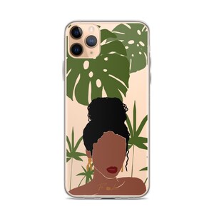 May include: A clear phone case with a design of a woman with dark brown skin and black hair, wearing gold earrings. The background is a light beige with green tropical leaves.