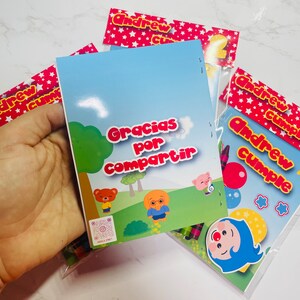 May include: A colourful thank you card with the text "Gracias por compartir" and a cartoon bear and dog. The card is part of a party favour bag with crayons and a clown sticker.